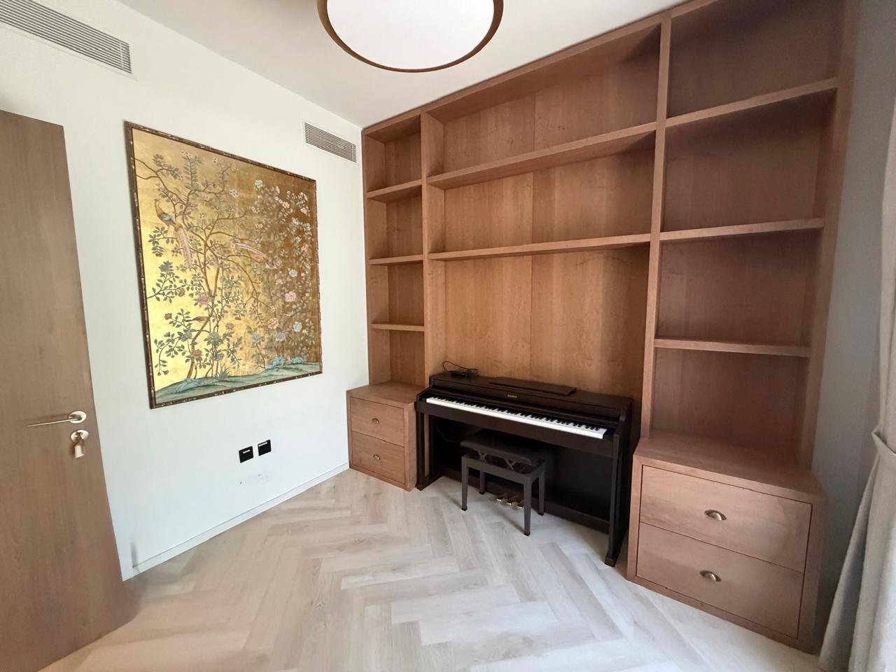 Angled view of the piano wall unit beside a framed mural