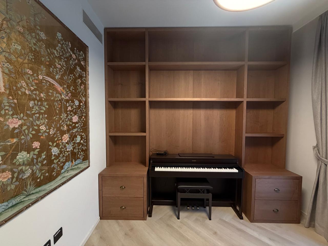 Oak veneer wall unit with shelves and drawers framing a digital piano