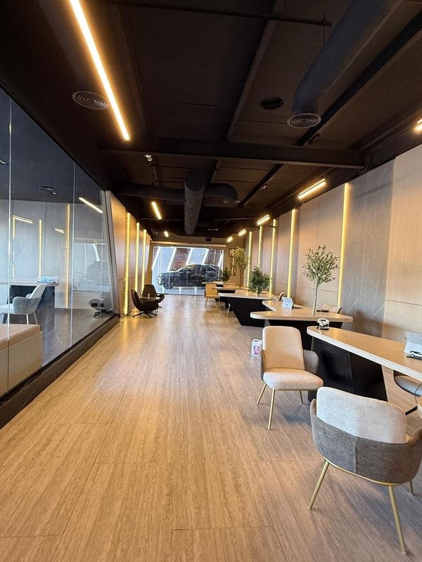Long showroom gallery with glazed wall and lit timber panels